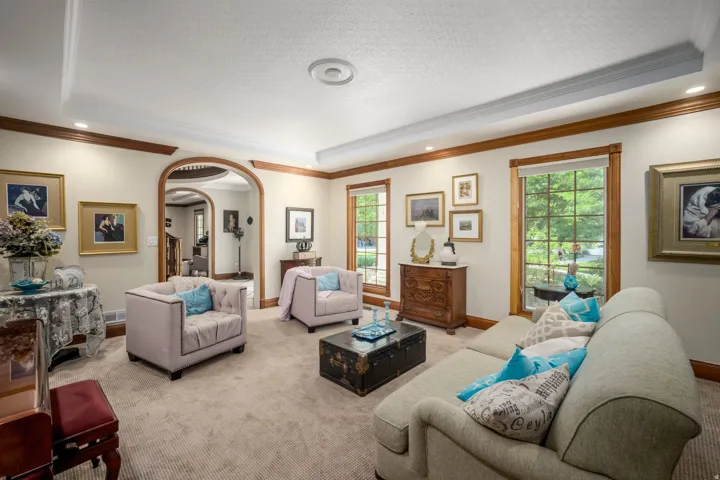 Recessed lighting illuminates a coffered ceiling, featuring decorative crown molding and wood-trim windows