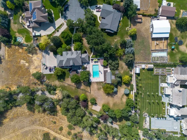 Expansive property featuring a swimming pool, multiple residential structures, large outbuilding, and mature landscaping