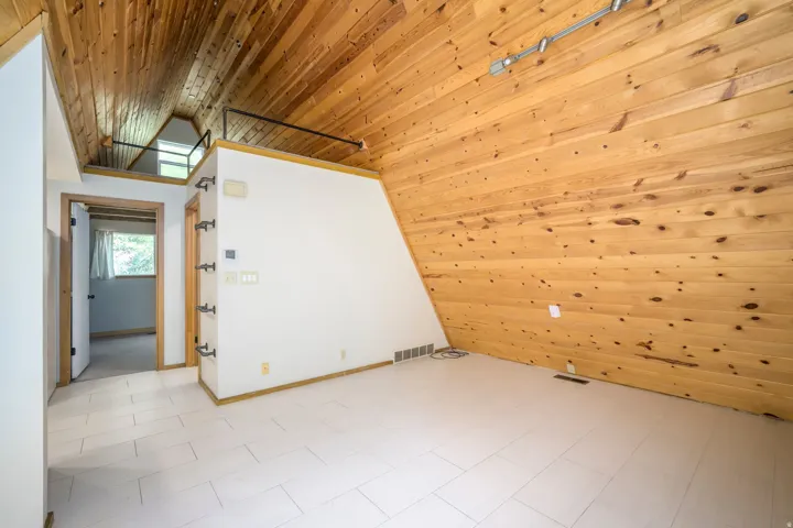 Vaulted wood-paneled ceiling, white tile flooring, and integrated track lighting