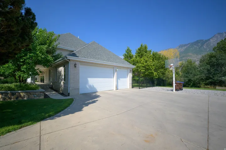 Two-car garage with white doors, light brick exterior, and a sloped driveway