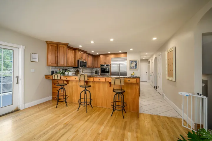 Kitchen featuring wood cabinetry, stainless steel appliances, a breakfast bar, and recessed lighting