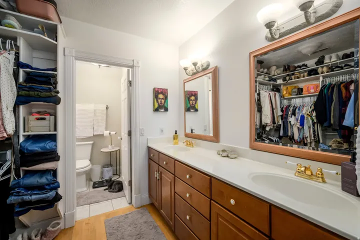 Dual vanity with wood-finish cabinetry, white countertops, and integrated sinks