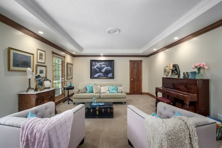 Recessed lighting, crown molding, tray ceiling detail, wood trim, and wood-finish door