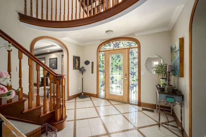 Grand entry with a curved staircase, wood banister, and an arched entryway