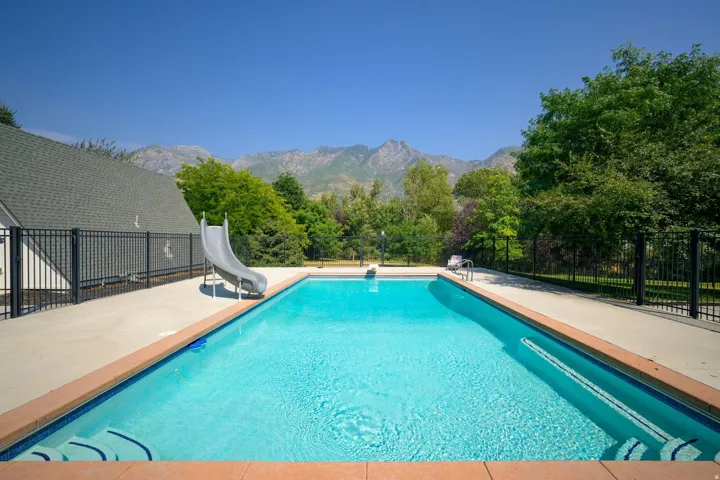 Expansive swimming pool with integrated steps, a poolside slide, and a concrete surround
