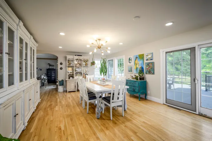 Light wood-finish flooring with recessed lighting and a contemporary chandelier