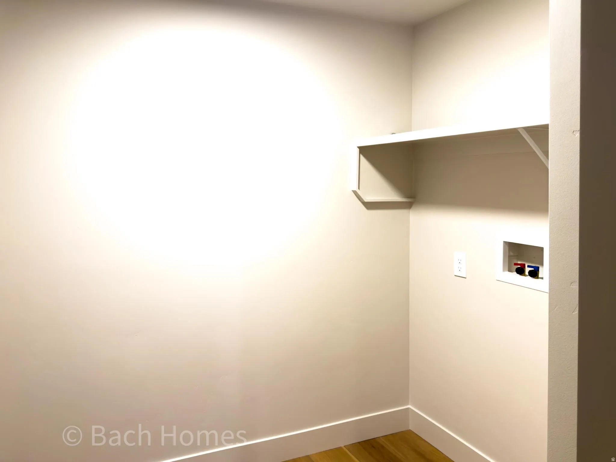 Integrated laundry connections with a built-in shelf and wood-finish flooring
