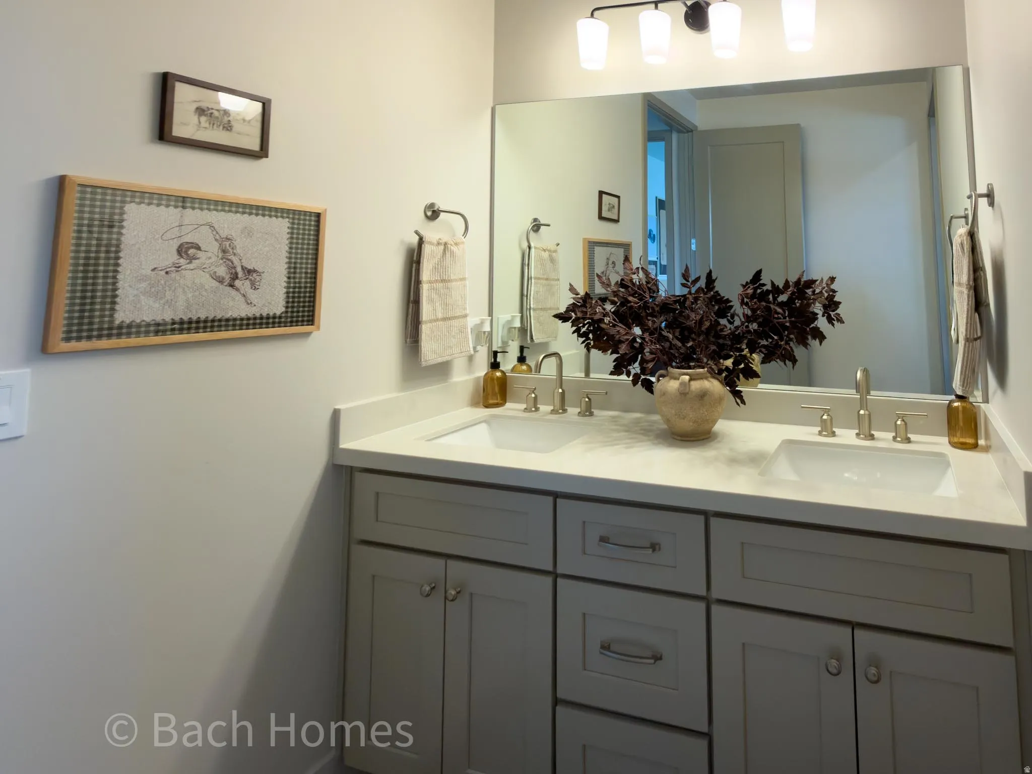 Dual vanity featuring light gray cabinetry, integrated sinks, brushed nickel fixtures, and a large wall-mounted mirror