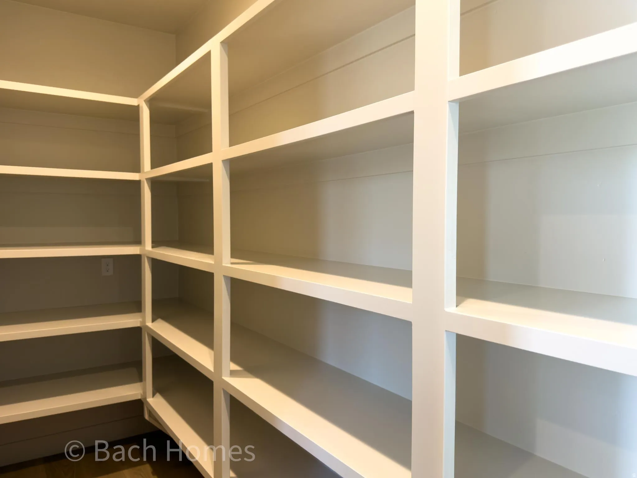 Built-in shelving with multiple levels, white finish, and integrated wall outlet