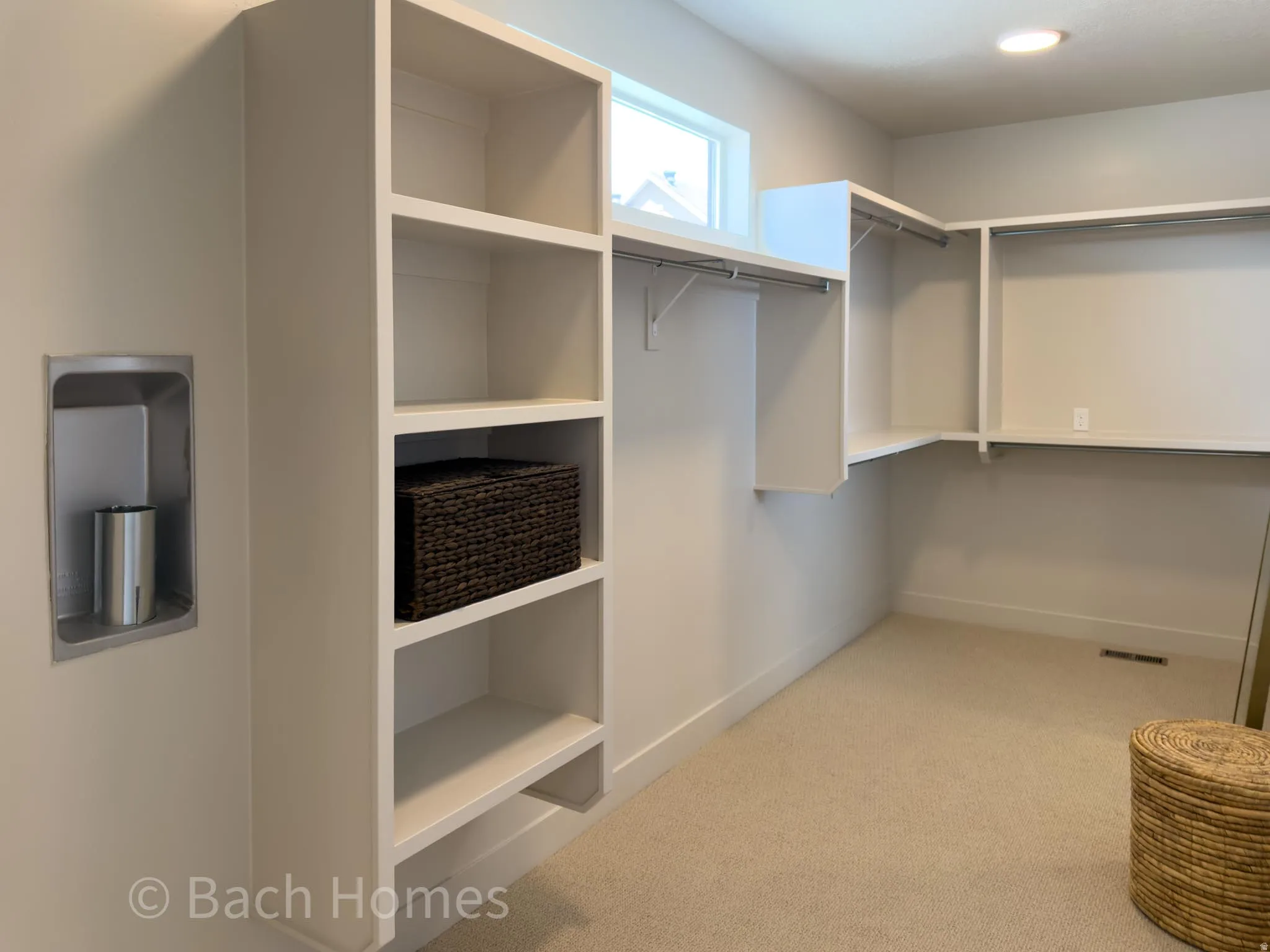 Spacious walk-in closet featuring built-in shelving, hanging rods, and an overhead window