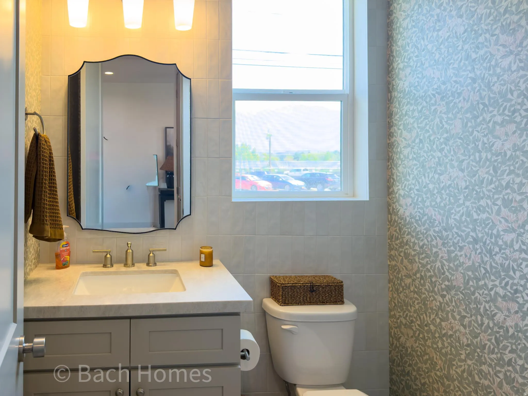 Windowed powder room featuring a single vanity with a countertop, undermount sink, and a framed mirror