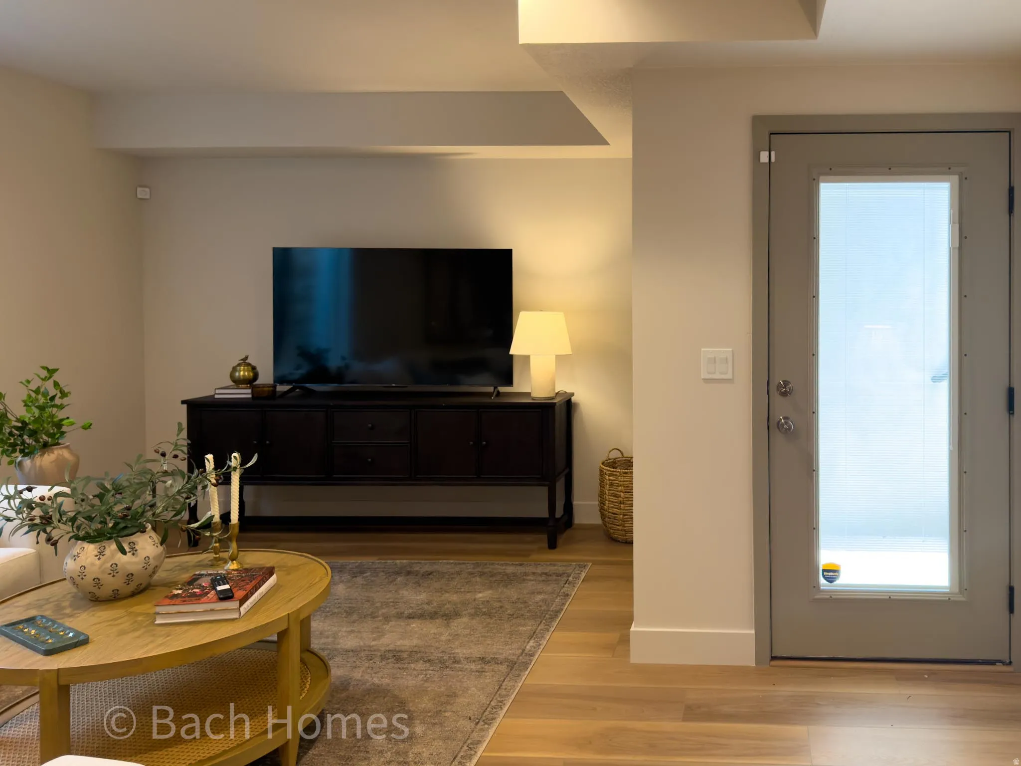 Wood-finish flooring, recessed ceiling lighting, light neutral wall paint, and a door with frosted glass panel