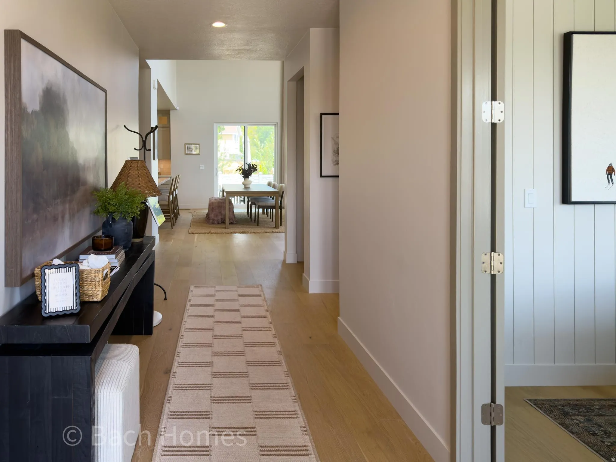 Welcoming entry hallway featuring warm wood-finish flooring, neutral wall tones, and geometric patterned runner
