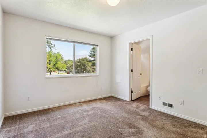 Bright secondary bedroom offering abundant natural light through large dual-pane windows, neutral wall finishes, and neutral-toned carpeting