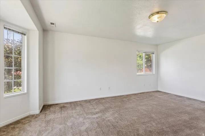 Bay window with grid patterns, neutral wall paint, and textured carpeting