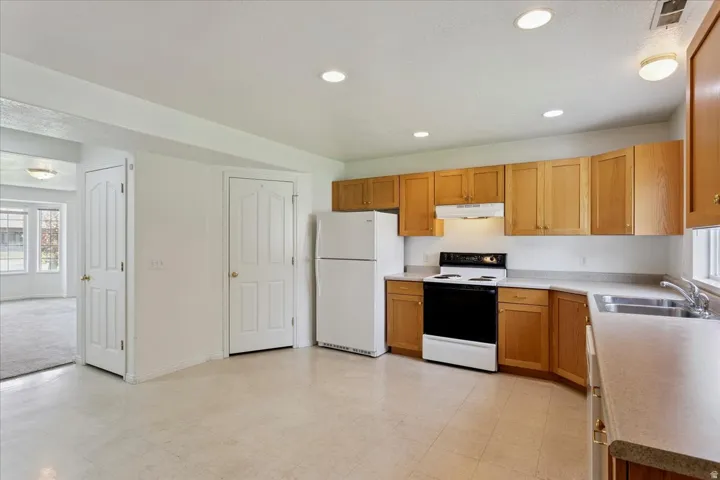 Spacious kitchen featuring wood-finish cabinetry, stainless steel appliances including a gas range and refrigerator, tile flooring, recessed ceiling lighting, and ample counter space