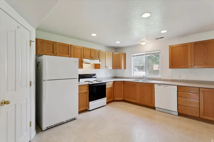 Kitchen featuring wood cabinetry, laminate countertops, a double-basin sink, and recessed lighting
