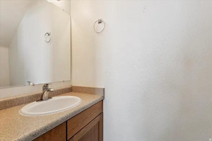 Bathroom featuring a wood-finish vanity with ample storage, quartz-style countertop, and an oval undermount sink with chrome faucet