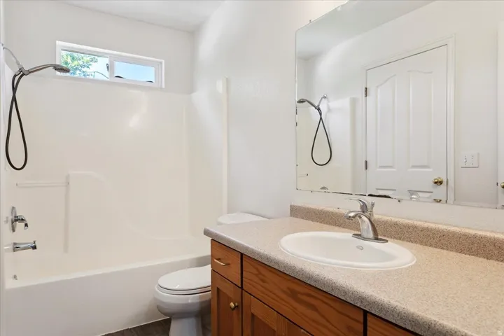Spa-inspired bathroom featuring a wood-finish vanity with dual storage drawers, a round ceramic sink, and a quartz composite countertop