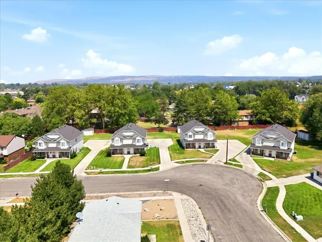 Prestigious cul-de-sac estate featuring elegant gray exterior with traditional architectural detailing, manicured landscaping with mature trees, circular driveway with fresh asphalt, and generous lot size