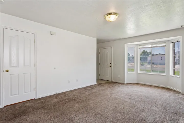 Spacious room with neutral walls, neutral carpet flooring, and abundant natural light from multiple large windows