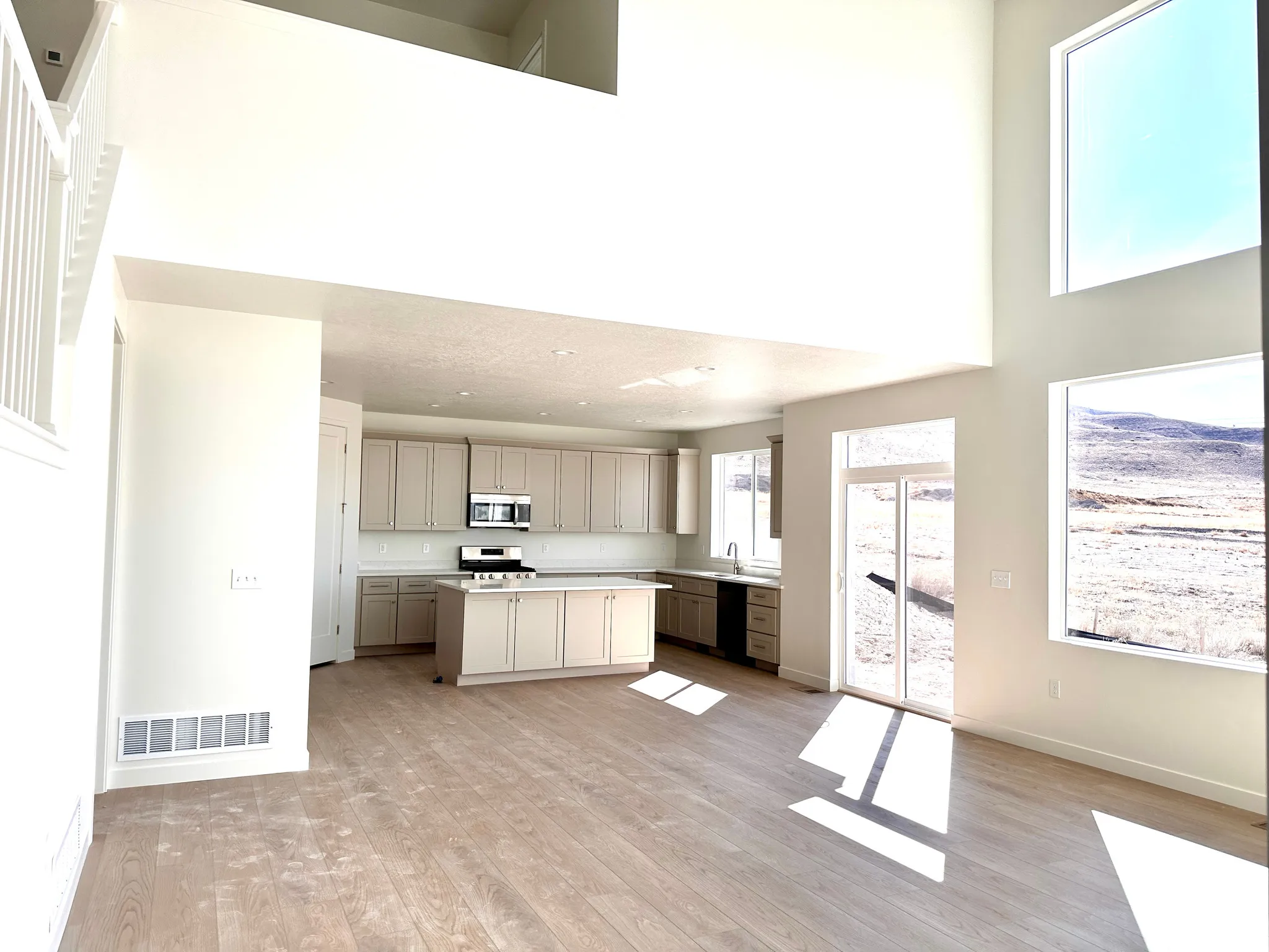 Open-concept living space featuring soaring ceilings with skylights, wood-finish flooring throughout, and abundant natural light