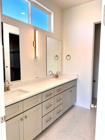 Spa-inspired primary bathroom featuring dual vanities with soft-close cabinetry, white quartz countertops, and brushed nickel hardware