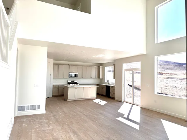 Open-concept living space featuring soaring ceilings with skylights, wood-finish flooring throughout, and abundant natural light
