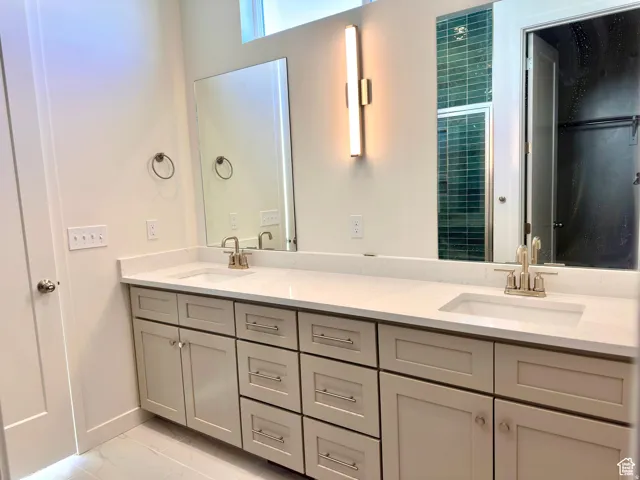 Spa-inspired primary bathroom featuring dual vanities with ample storage, white quartz countertops, polished nickel fixtures, and recessed lighting