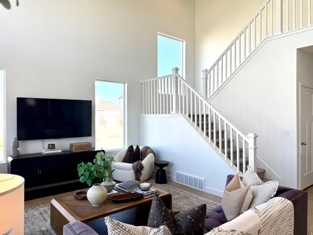 Two-story living area featuring a prominent staircase with white balusters and carpeted treads