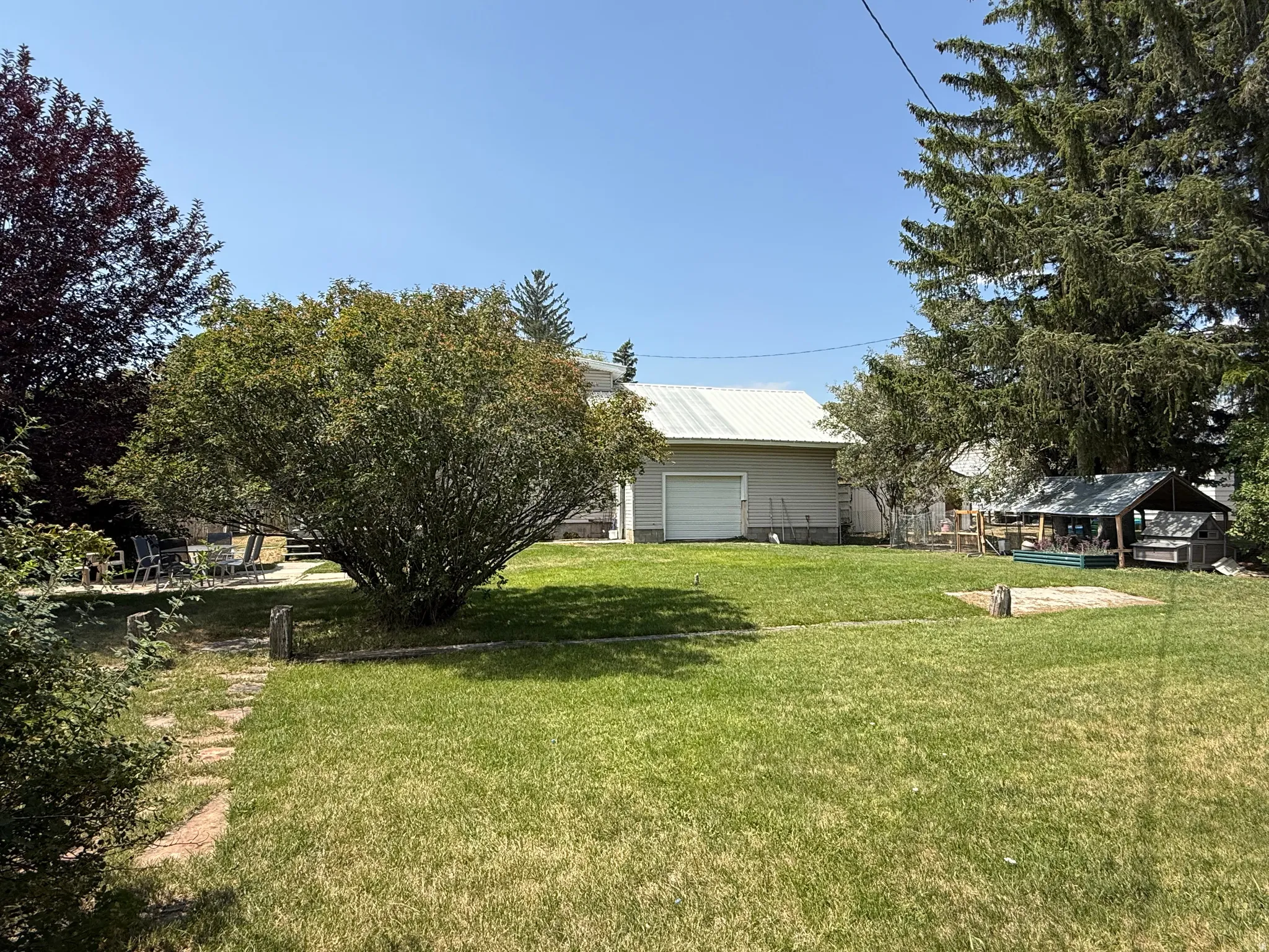 Expansive green lawn with mature trees and a stone pathway leading to a patio area