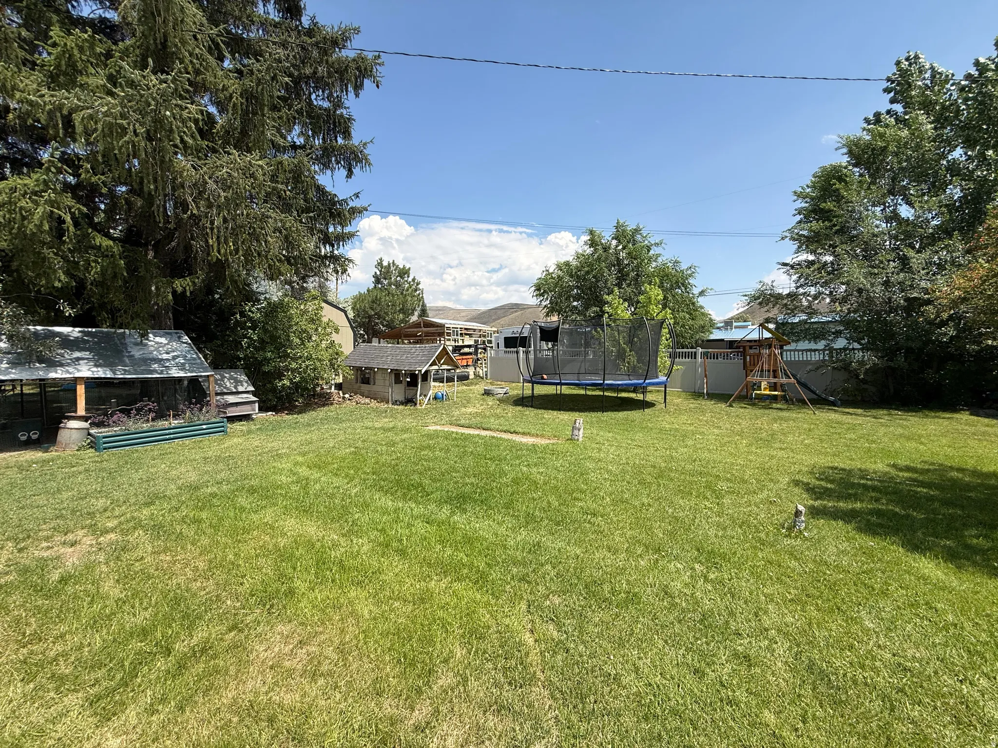 Expansive green lawn with mature trees providing partial shade