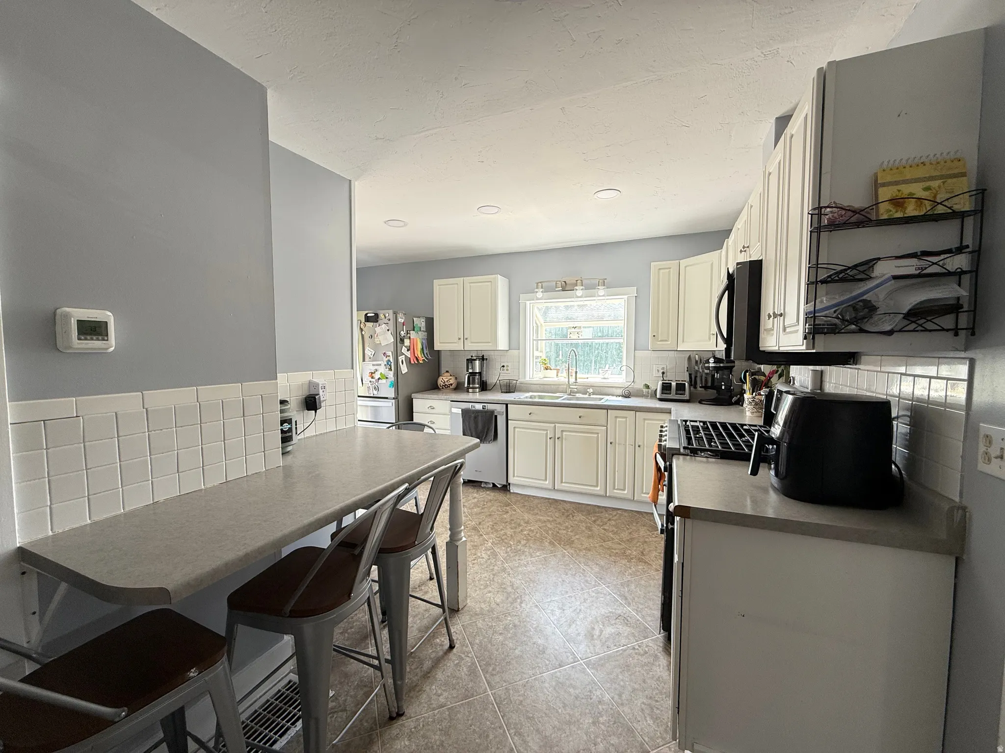 Kitchen featuring white cabinetry, tile backsplash, built-in breakfast bar, and stainless steel appliances