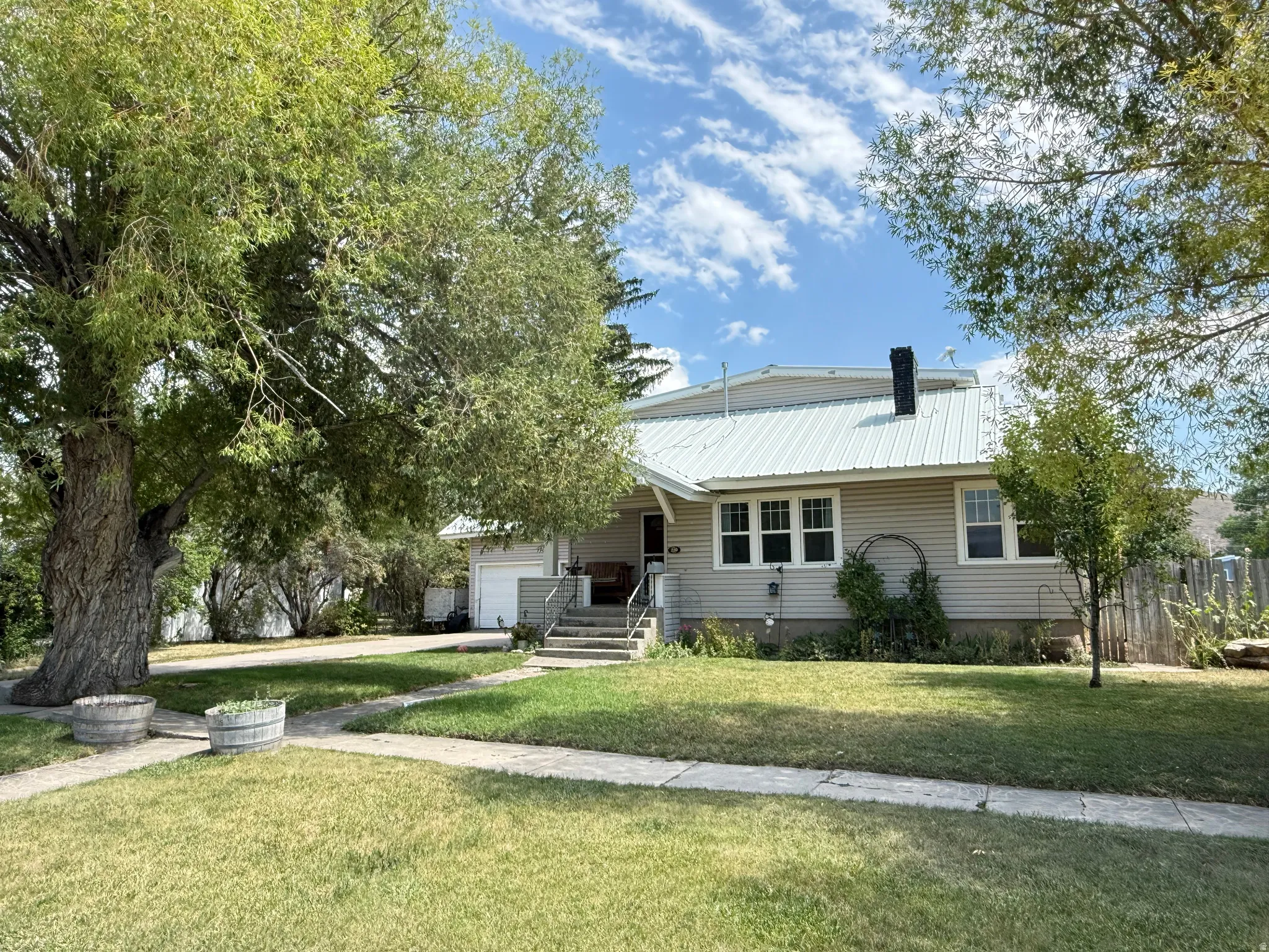Charming farmhouse-style residence featuring a pitched metal roof, horizontal siding exterior, and covered front porch with steps