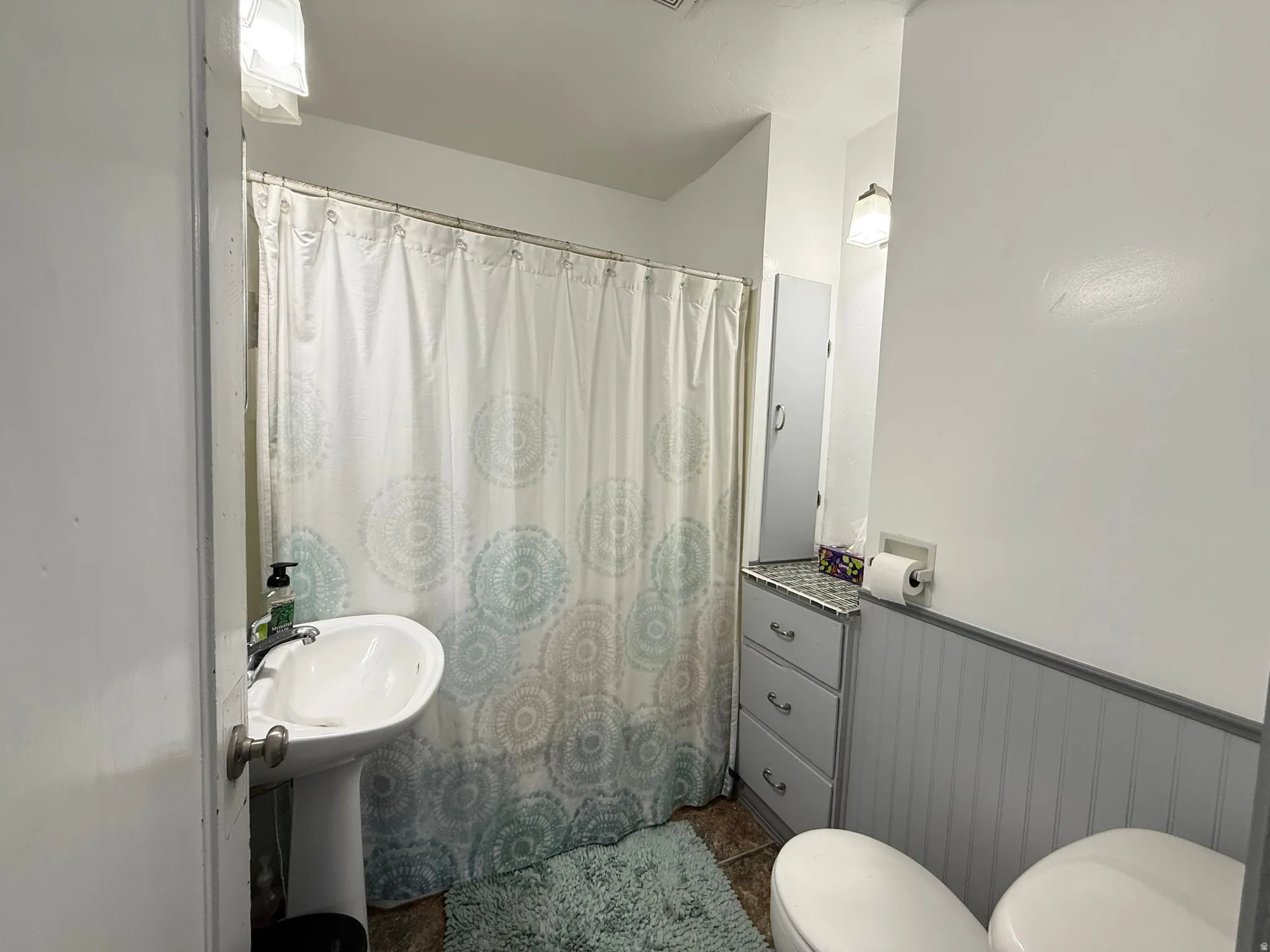 Functional full bathroom featuring a pedestal sink, toilet, and bathtub with shower enclosure