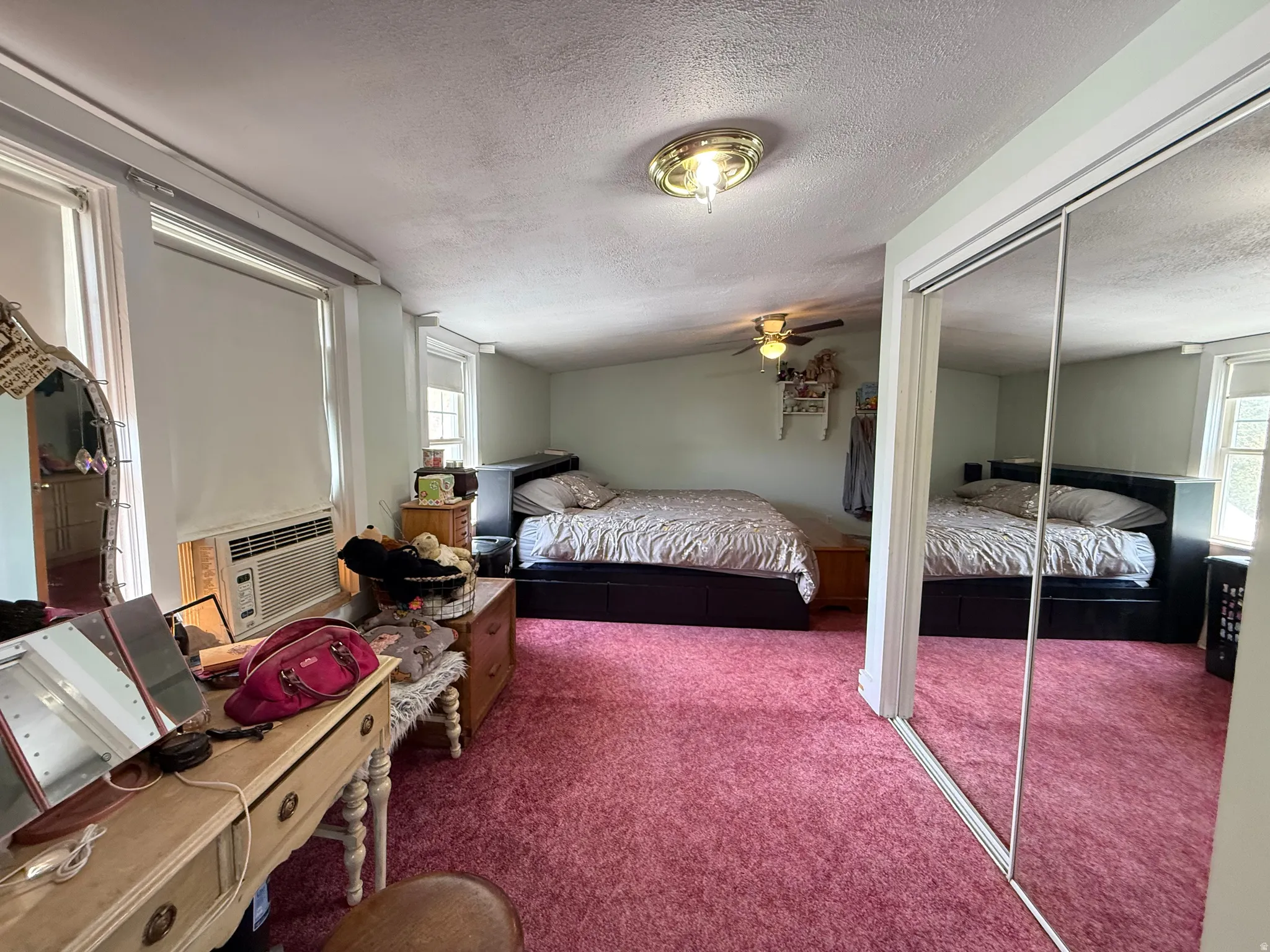 Spacious primary bedroom suite with mirrored sliding closet doors, plush carpeting, and abundant natural light from multiple windows