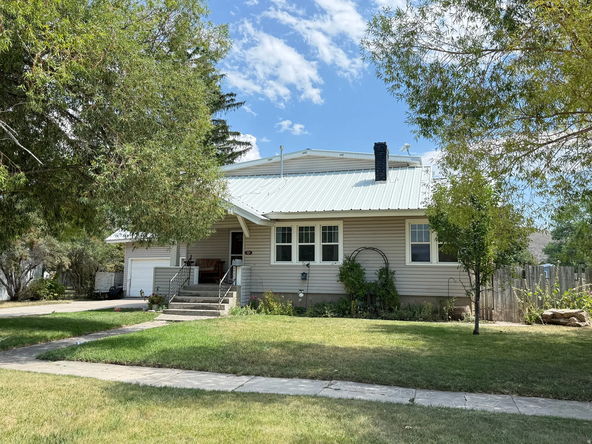 Charming farmhouse-style residence featuring a metal roof, horizontal siding exterior, and covered front porch with entry stairs