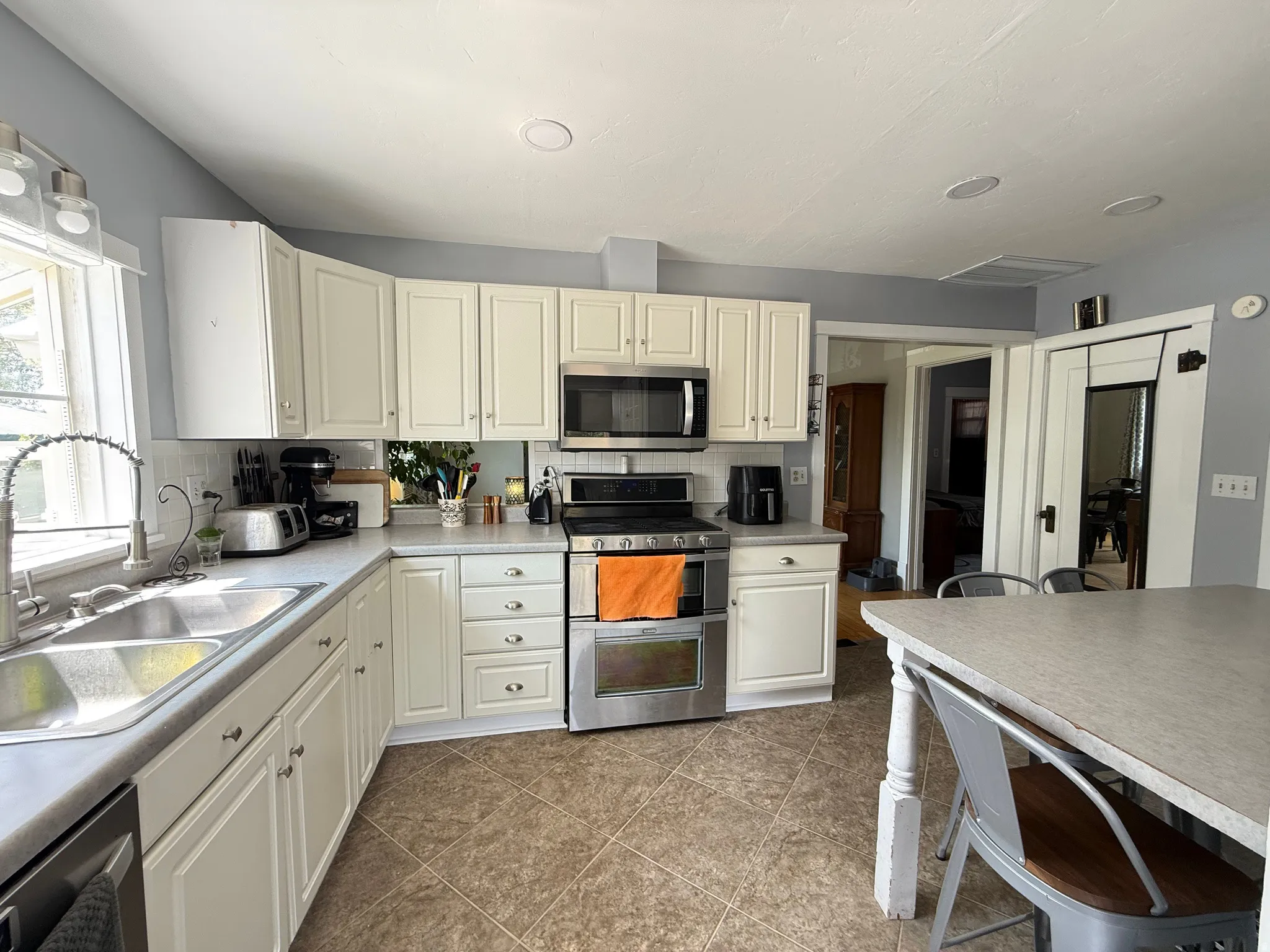 Kitchen featuring stainless steel appliances, white cabinetry, double basin sink, and recessed lighting