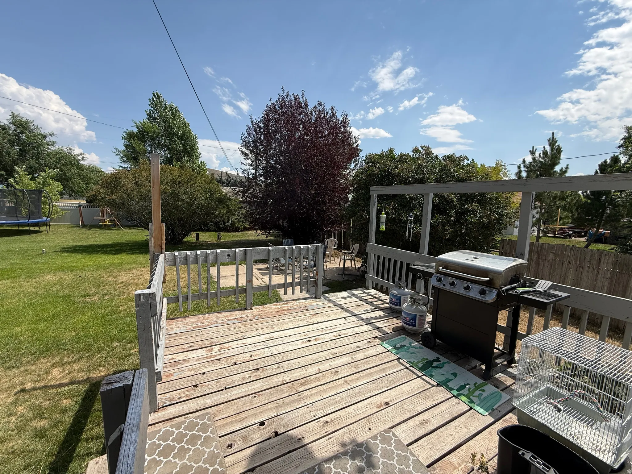 Expansive wood deck with railing overlooking a substantial grassy yard