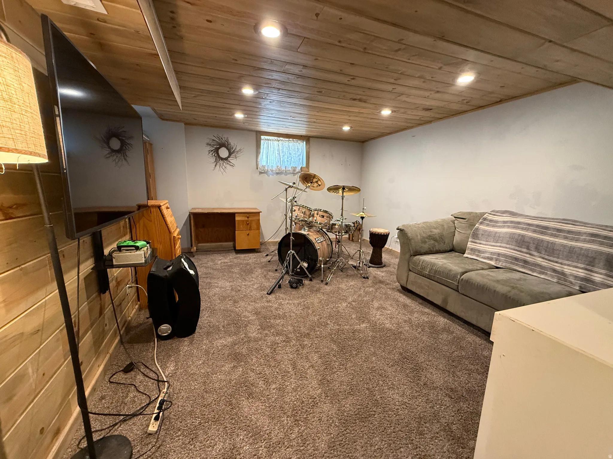 Versatile recreation room featuring wood-finish ceiling with recessed lighting, carpeted flooring, built-in cabinetry, and a flat-screen television mount
