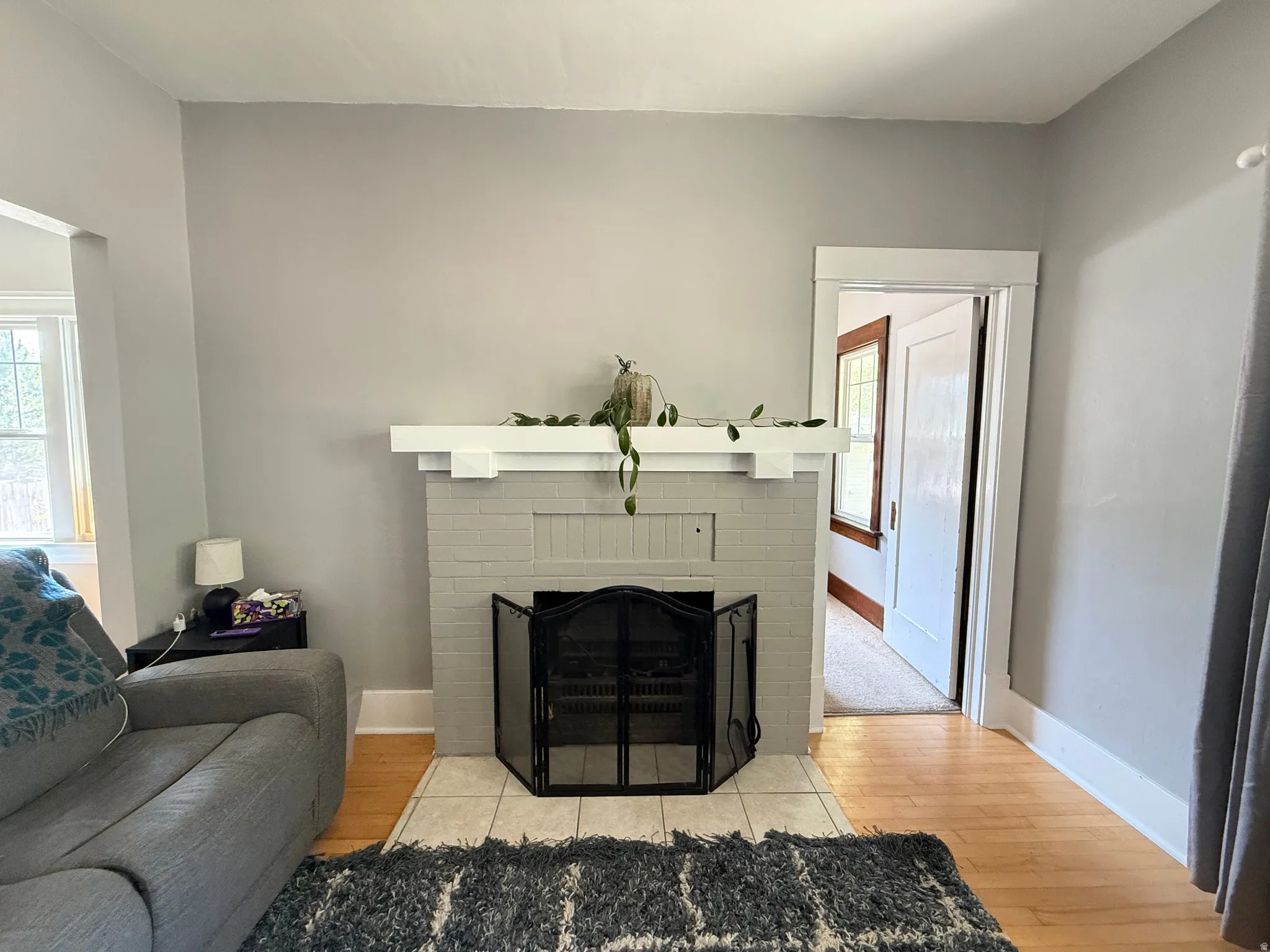 Brick fireplace with a white mantel, complemented by light wood-finish flooring and white trim