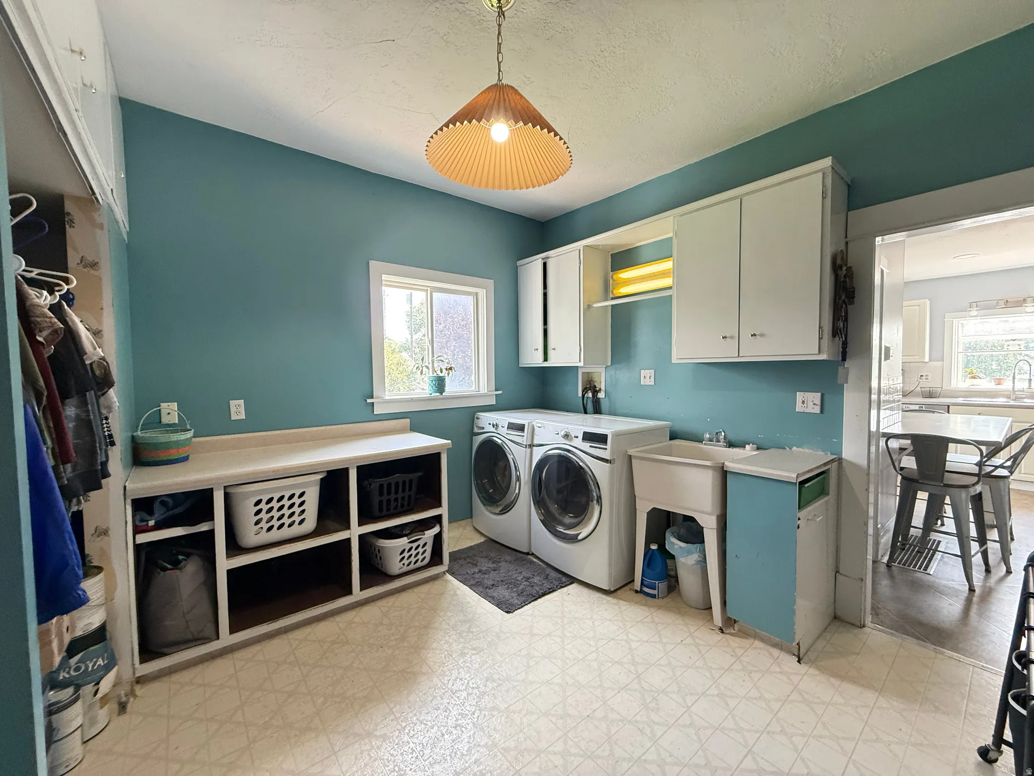 Laundry room featuring a utility sink, built-in shelving, white cabinetry, and patterned flooring