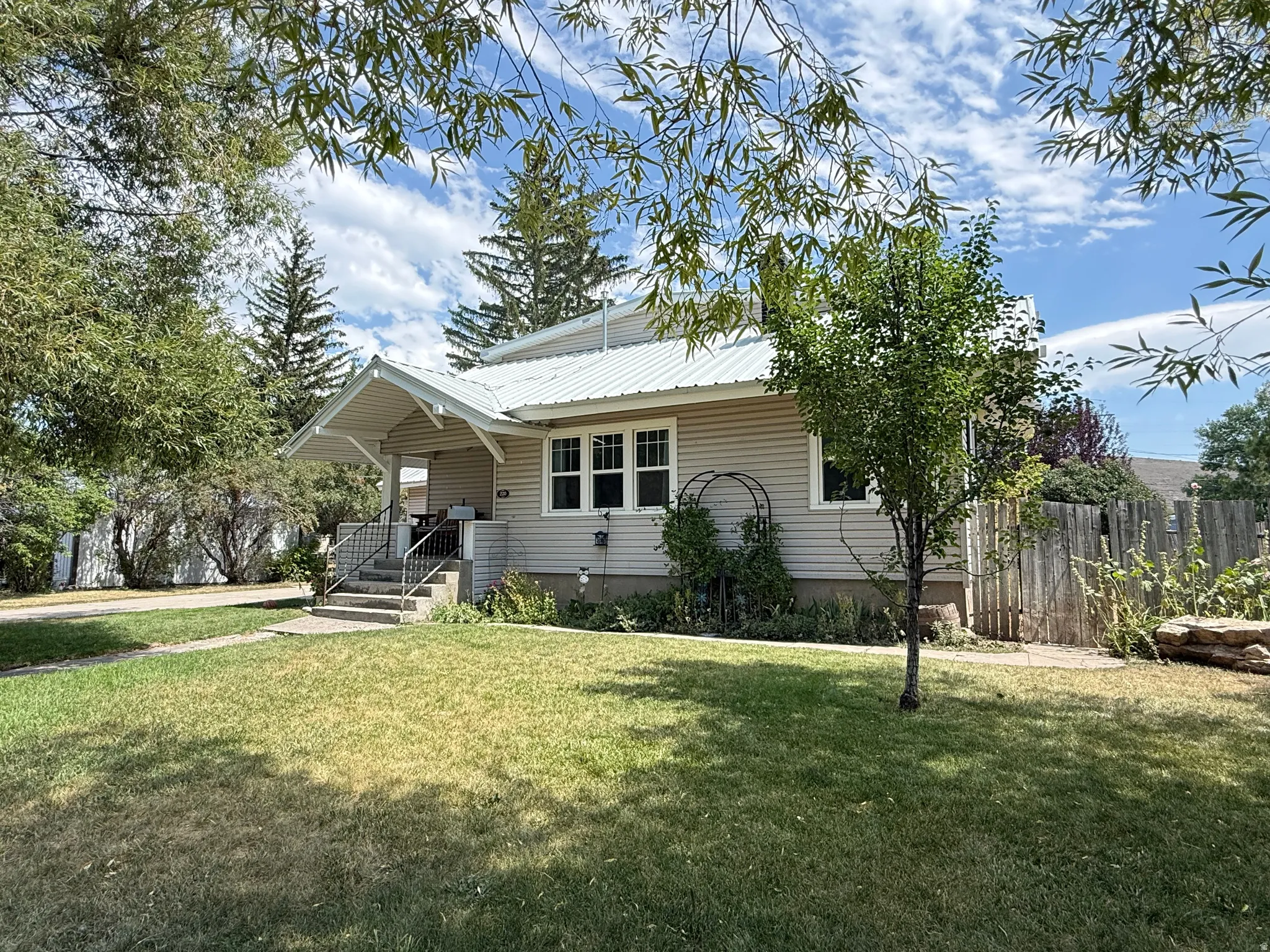 Charming cottage-style home featuring a gabled roof, horizontal siding exterior, and covered front porch with steps