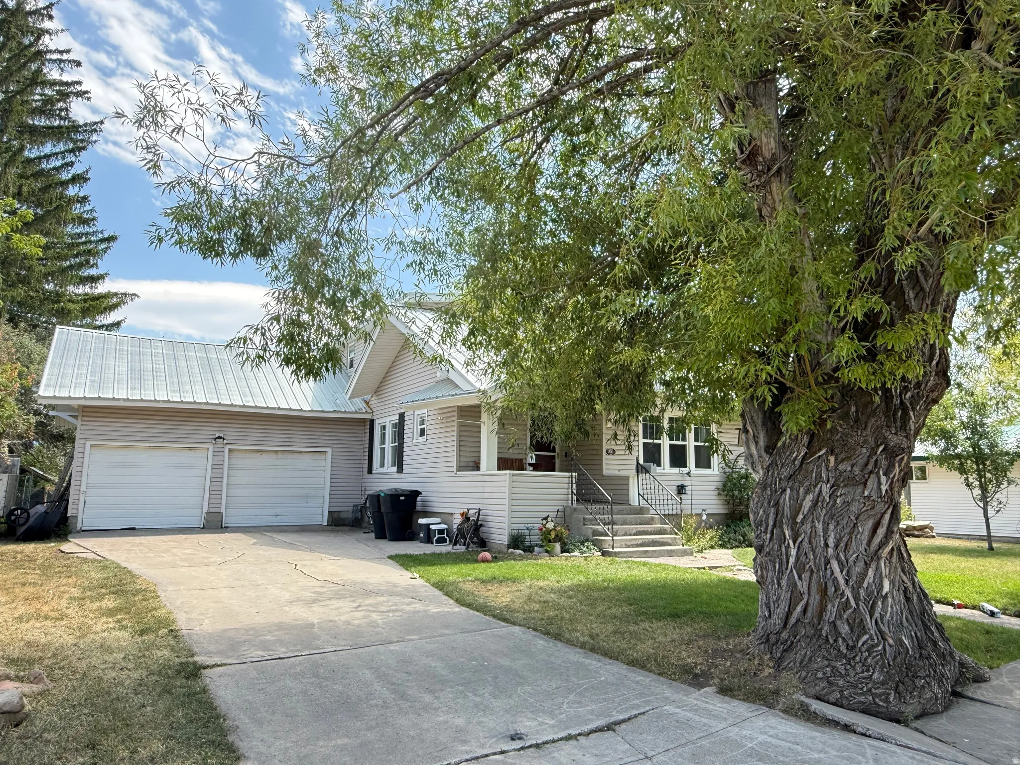 Charming single-story residence featuring a two-car attached garage, metal roof, and classic siding exterior