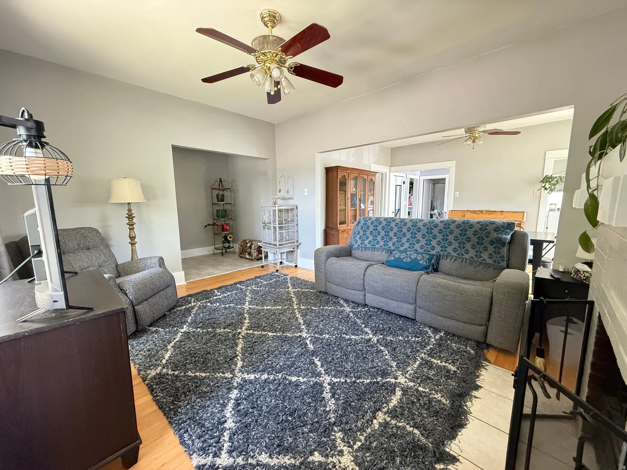 Spacious living room featuring wood-finish flooring, a geometric area rug, and abundant natural light from multiple windows