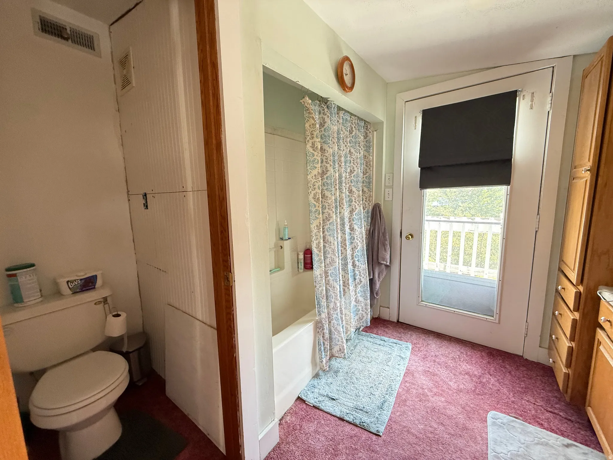Tub/shower combination, built-in storage cabinet, solid surface countertop, wood cabinetry, and exterior access