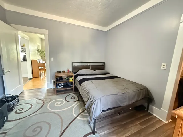 Spacious secondary bedroom featuring neutral wall finishes, wood-finish flooring, and abundant natural light from multiple windows
