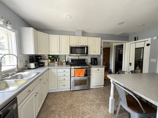 Kitchen featuring stainless steel appliances, white cabinetry, double basin sink, and recessed lighting