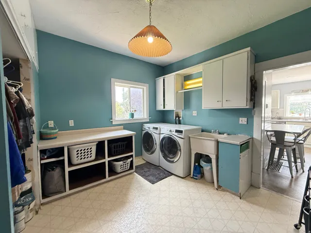 Laundry room featuring a utility sink, built-in shelving, white cabinetry, and patterned flooring
