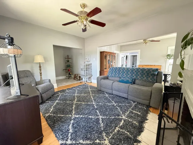 Spacious living room featuring wood-finish flooring, a geometric area rug, and abundant natural light from multiple windows